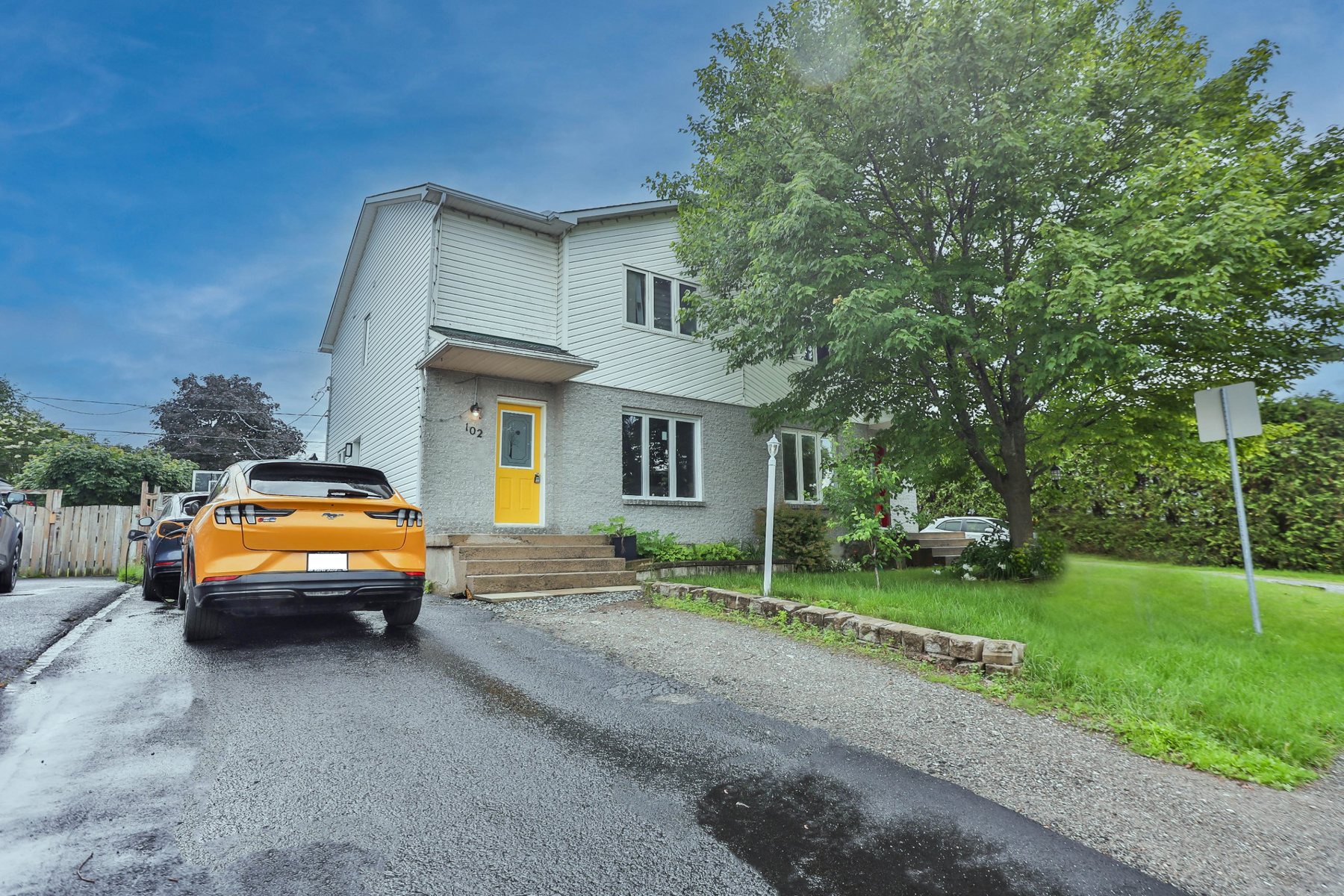 Two-storey home with a yellow front door and mature tree, Ottawa